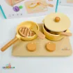 My Little Cooking Playset wooden toy stove close-up showing two control knobs, a yellow frying pan with toy steak and spatula, and a cooking pot with a partially open lid.